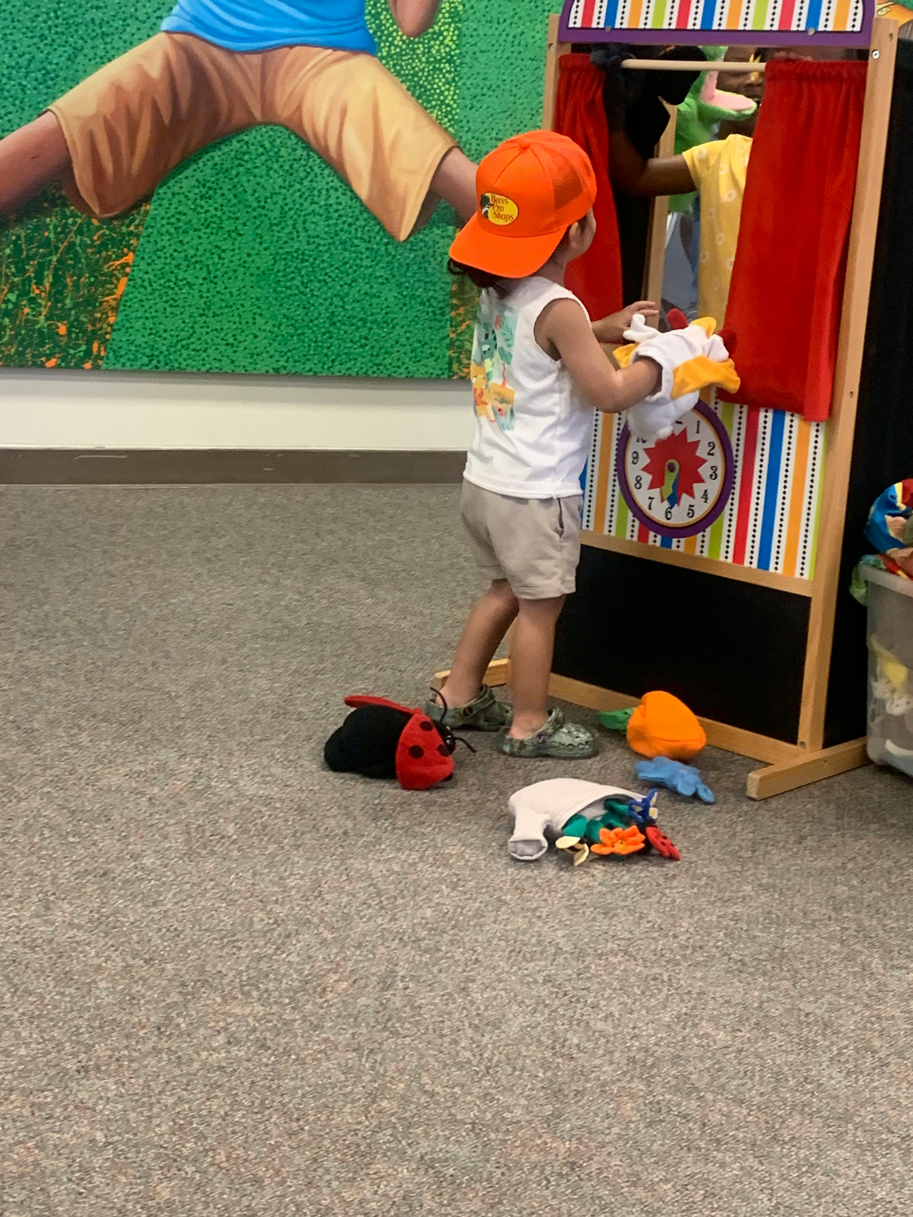 Child playing with hand puppets near a puppet theater
