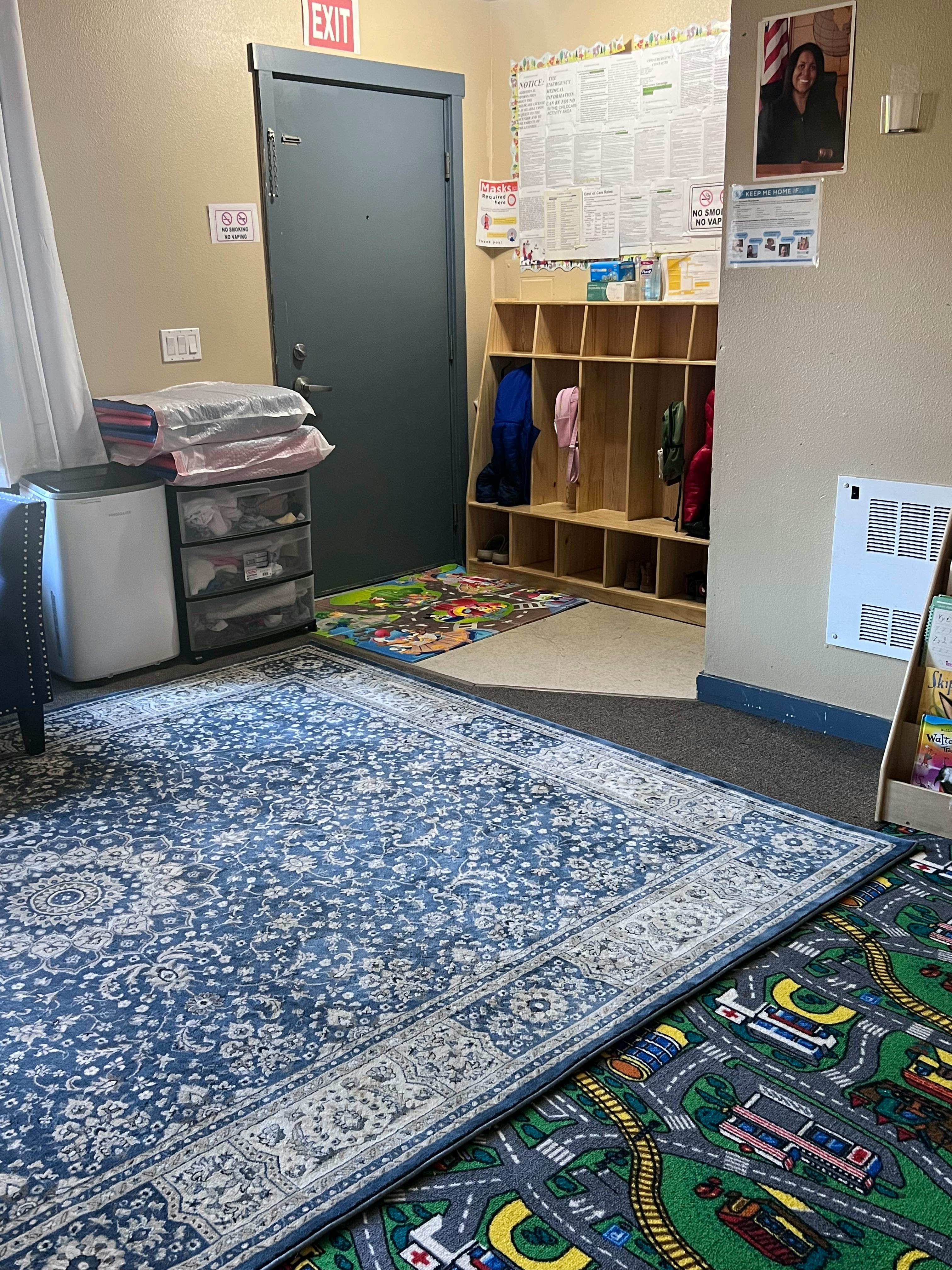 Classroom with an exit door, cubbies, and two rugs