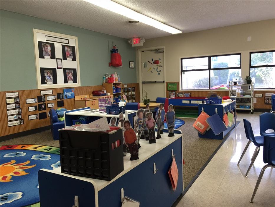 An empty early childhood classroom with windows and an exit sign