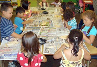 Children at a table covered in newspaper doing an activity