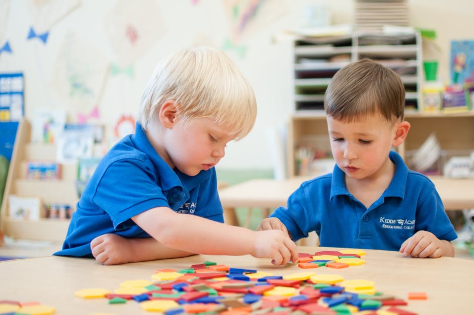 Two children playing with colorful shapes at a table
