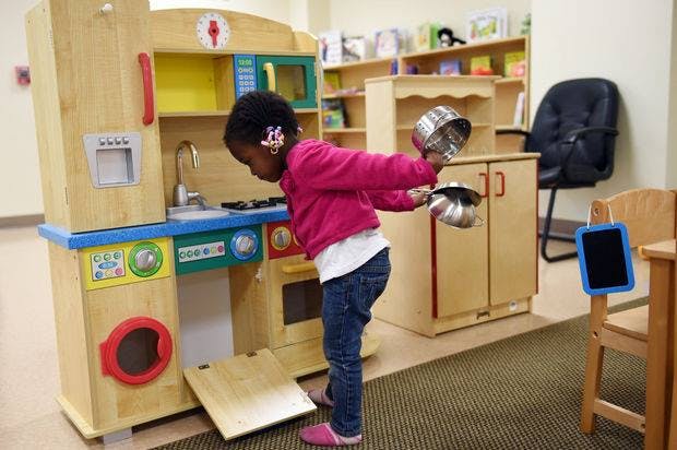 Child playing with a toy kitchen set, holding pots