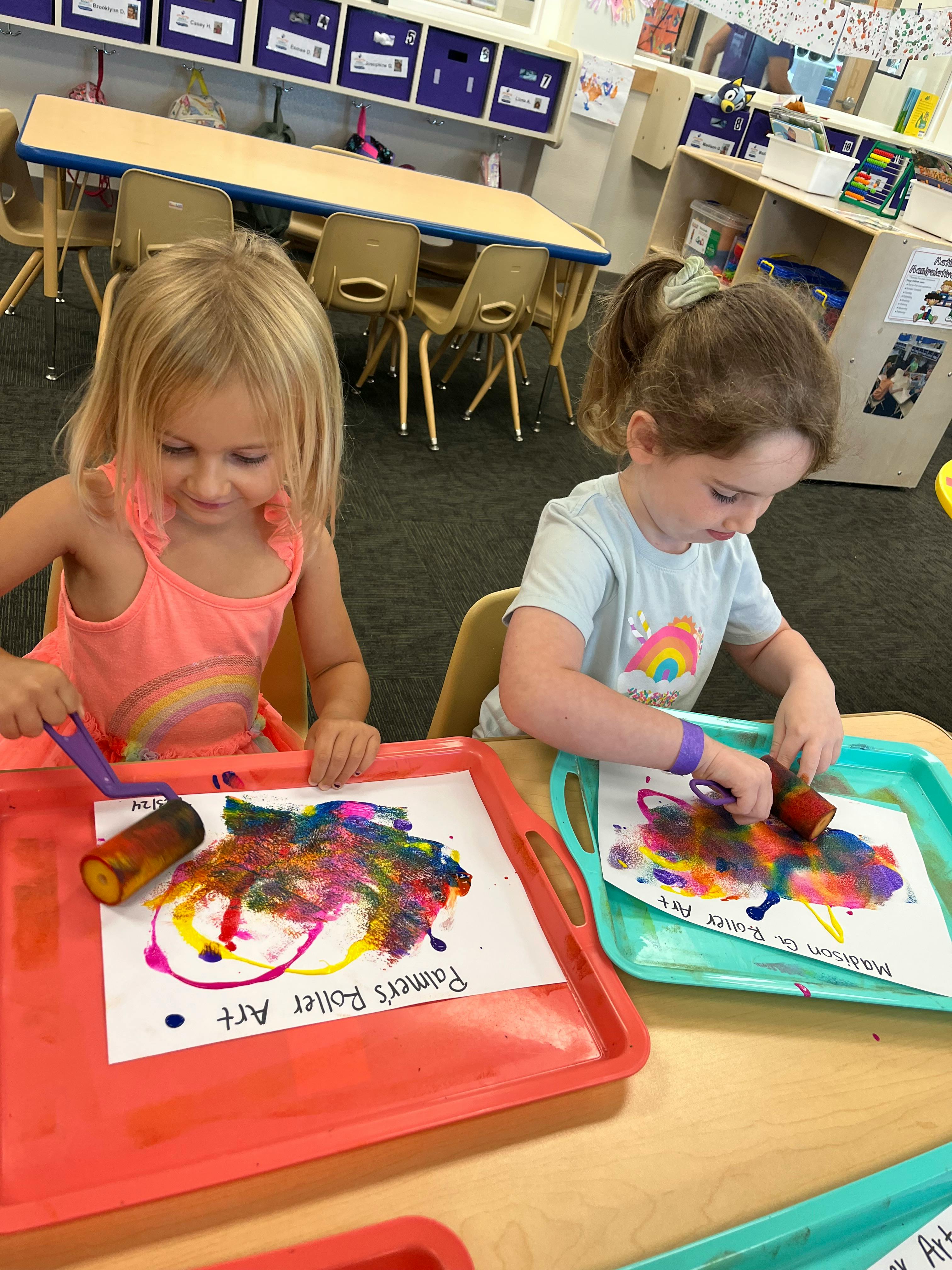 Two children creating roller art in a classroom