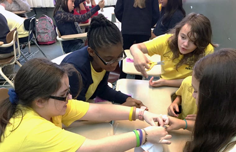 Teens in a classroom working on a project together