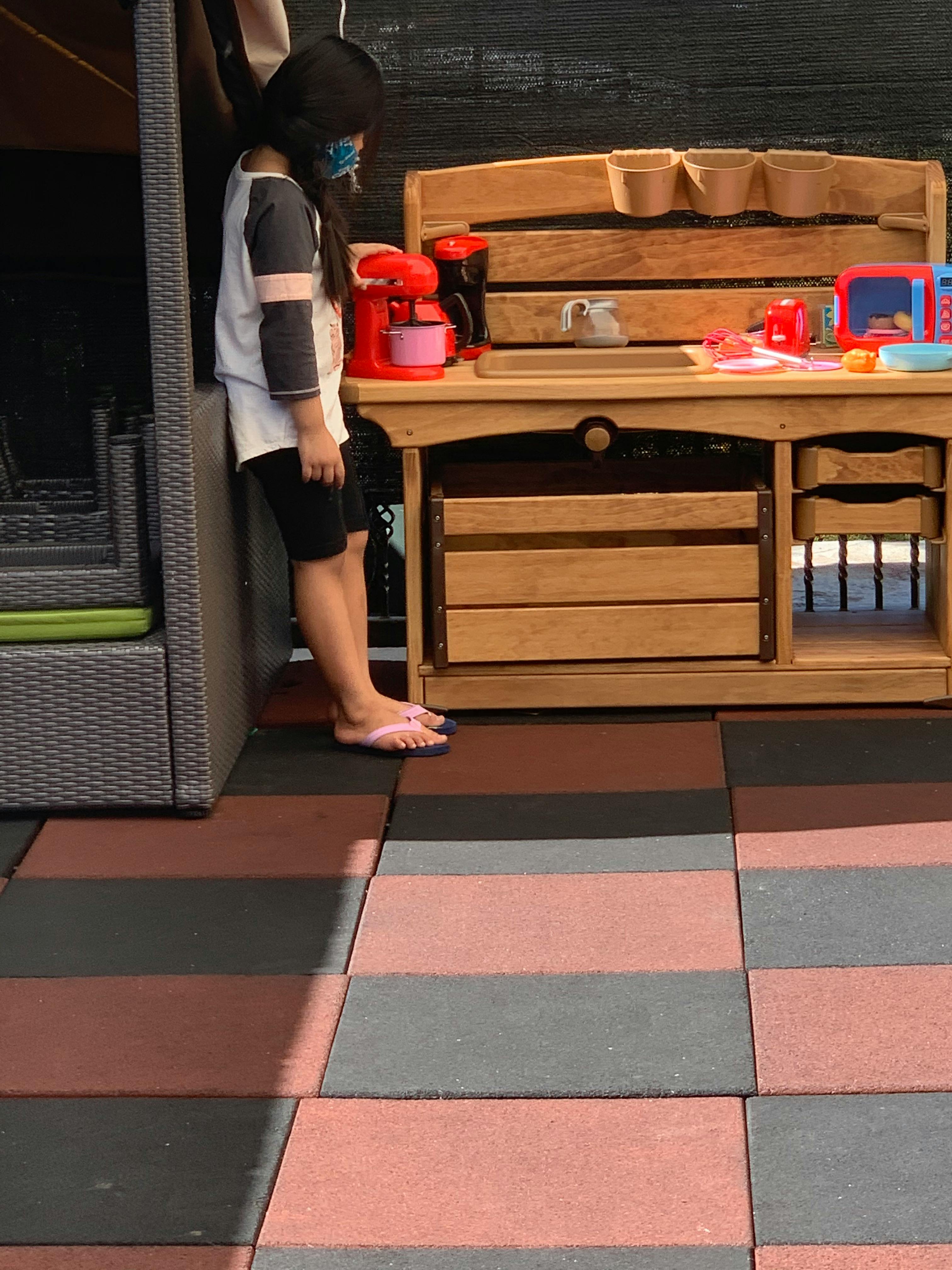 Child lying on a lounge chair next to a play kitchen