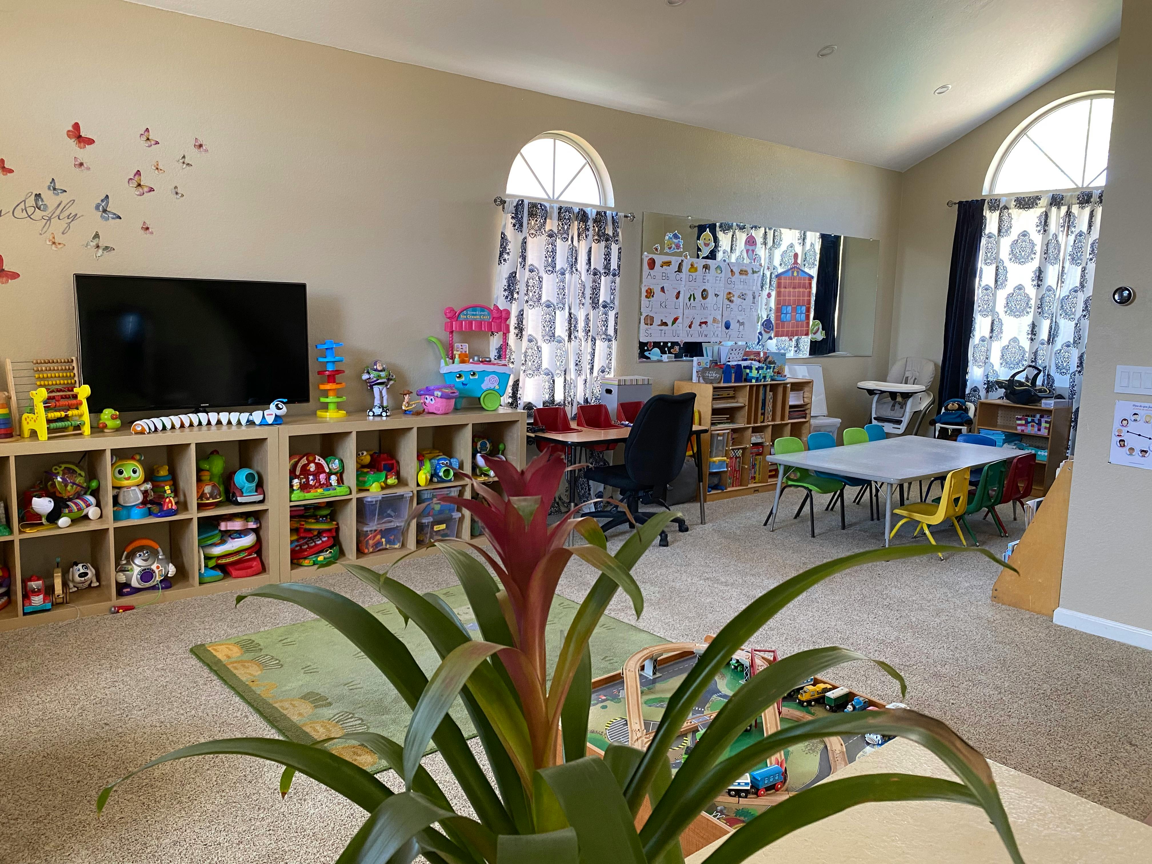 Playroom with toys on shelves, tables, and chairs