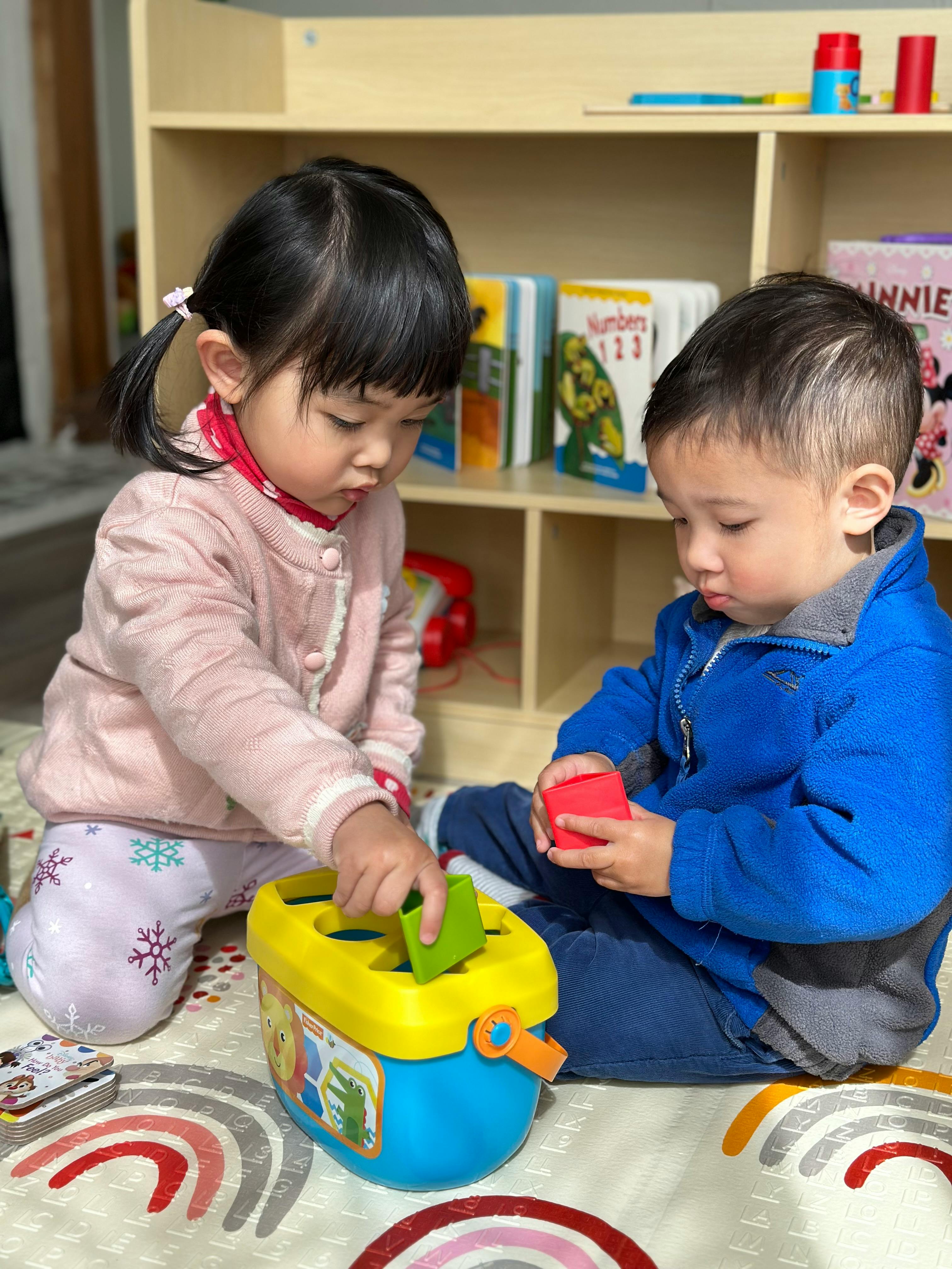 Two children playing with a shape sorter toy