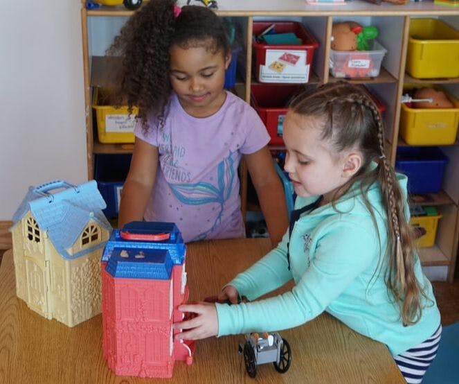 Two children playing with toys at a table