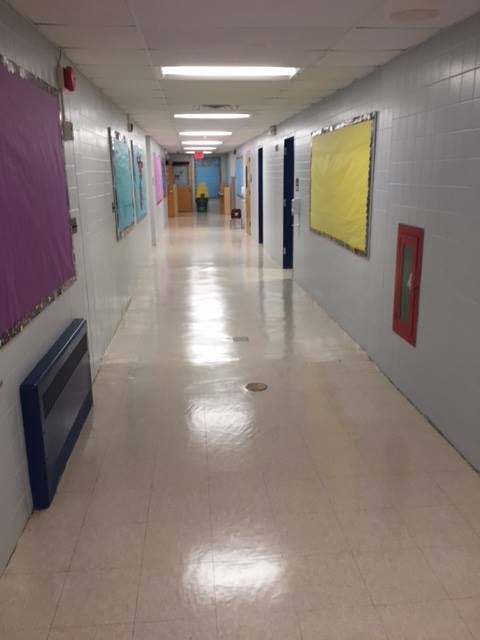Long empty school hallway with bulletin boards on the walls