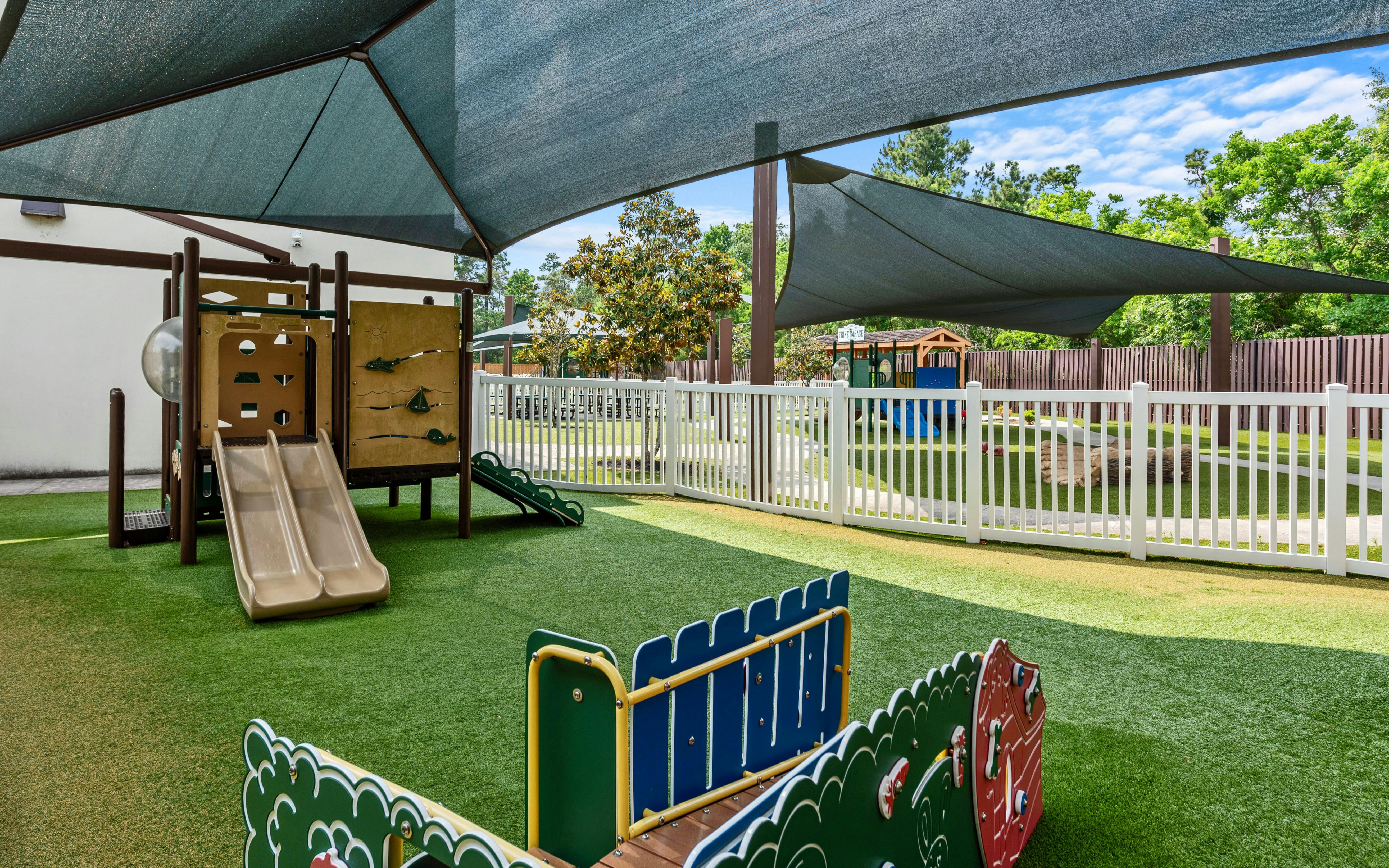 Outdoor playground with artificial turf, brown slides, and climbing structures