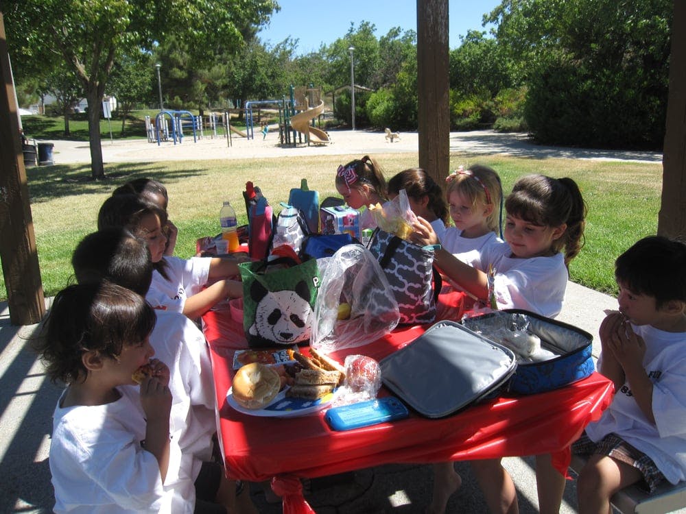 Children eating at a picnic table outdoors
