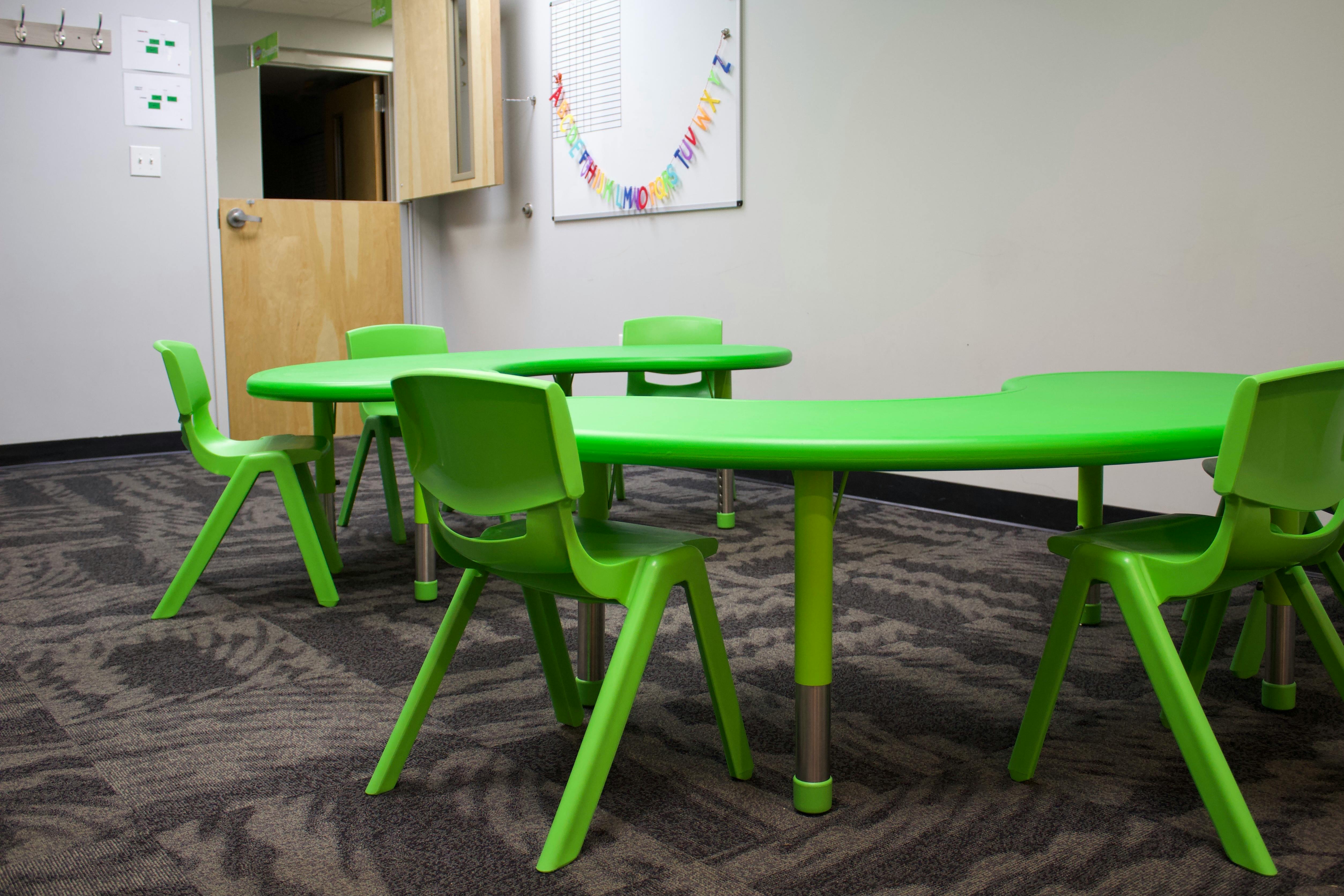Green tables and chairs in a classroom