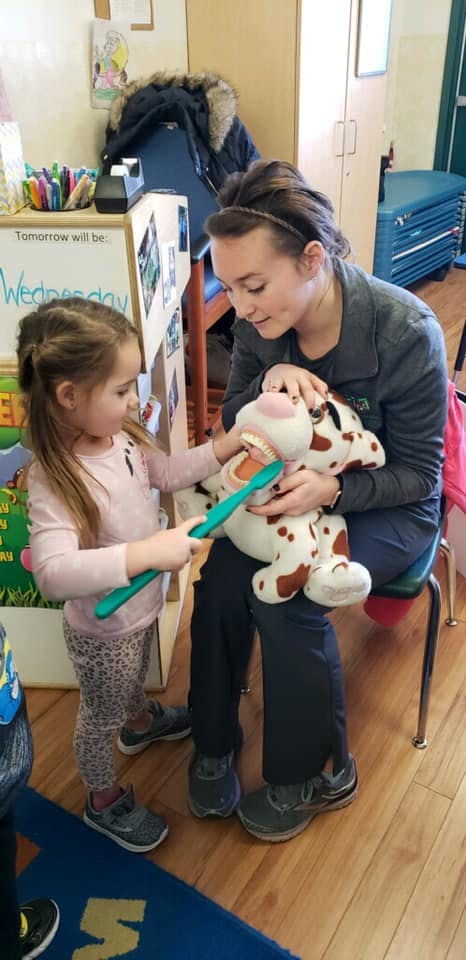 Child brushing teeth of a stuffed animal with a person