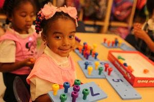 Child playing with colorful pegs on a board
