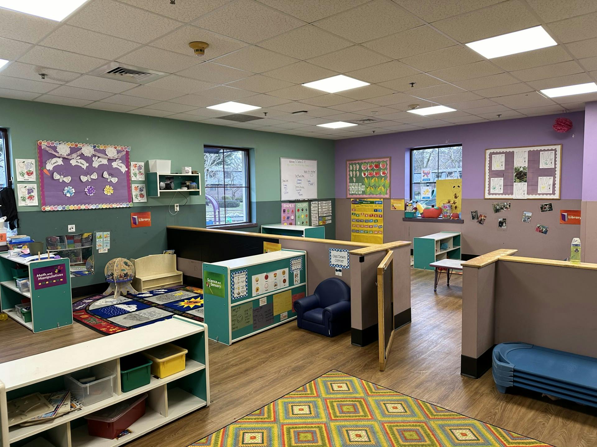 Classroom with colorful walls, rugs, activity centers, and bulletin boards
