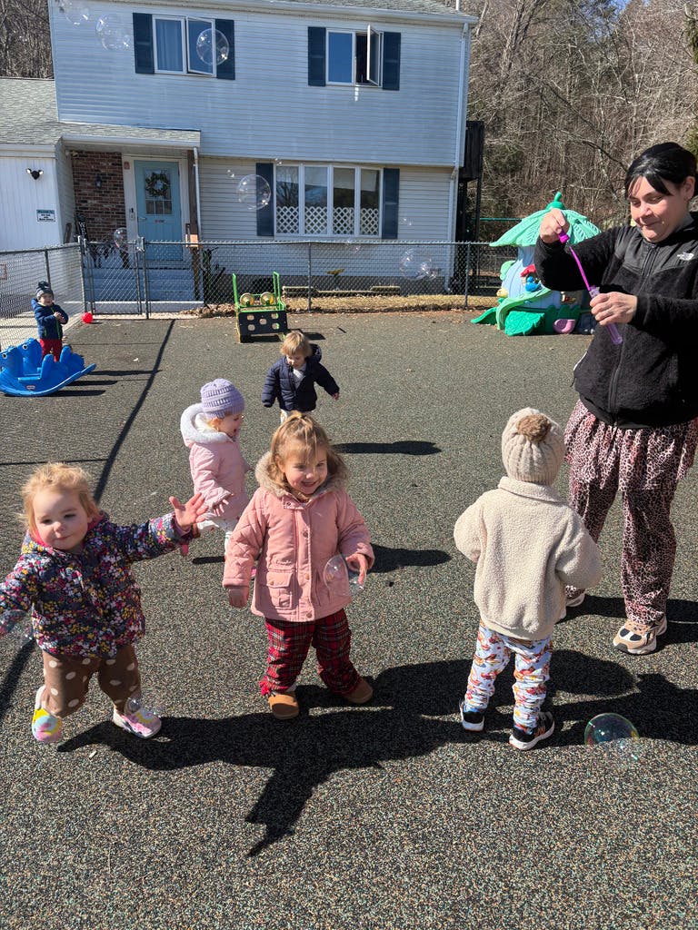 Person blowing bubbles for several children on a playground