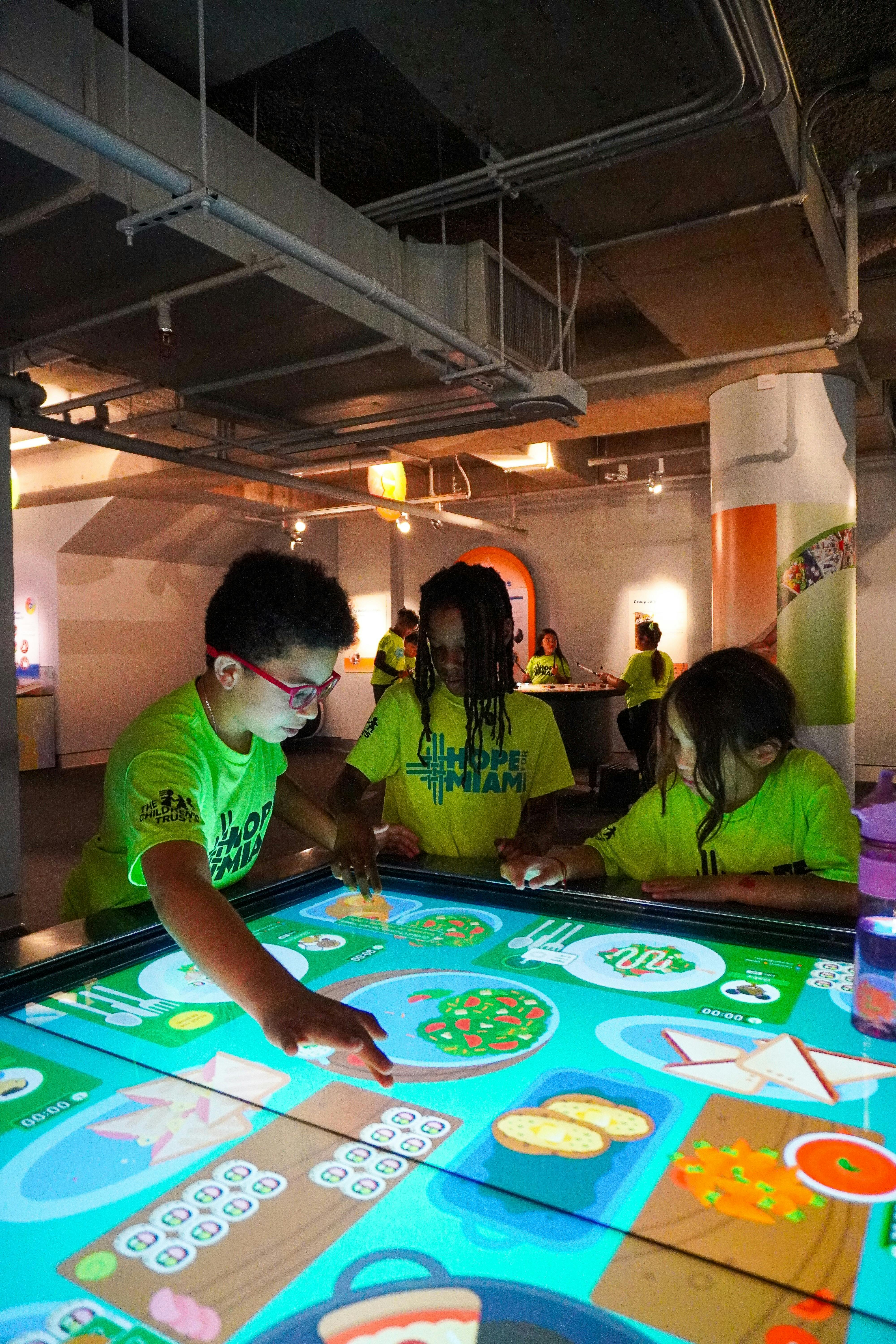 Three children playing with an interactive digital table in a museum