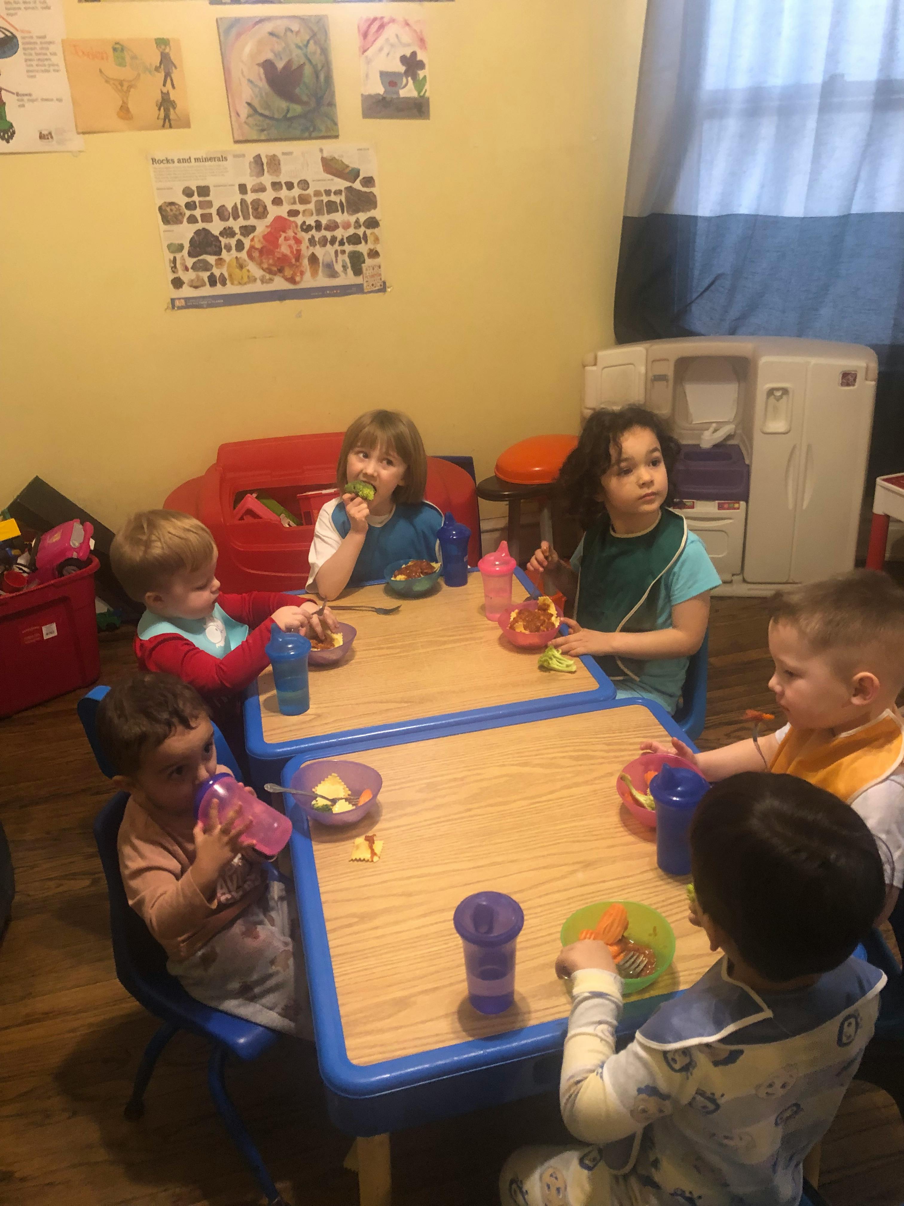 Children sitting at tables eating and eating snacks