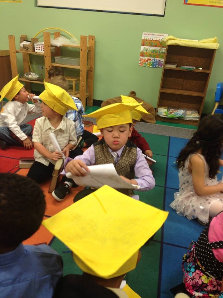 Children wearing yellow graduation caps in a classroom