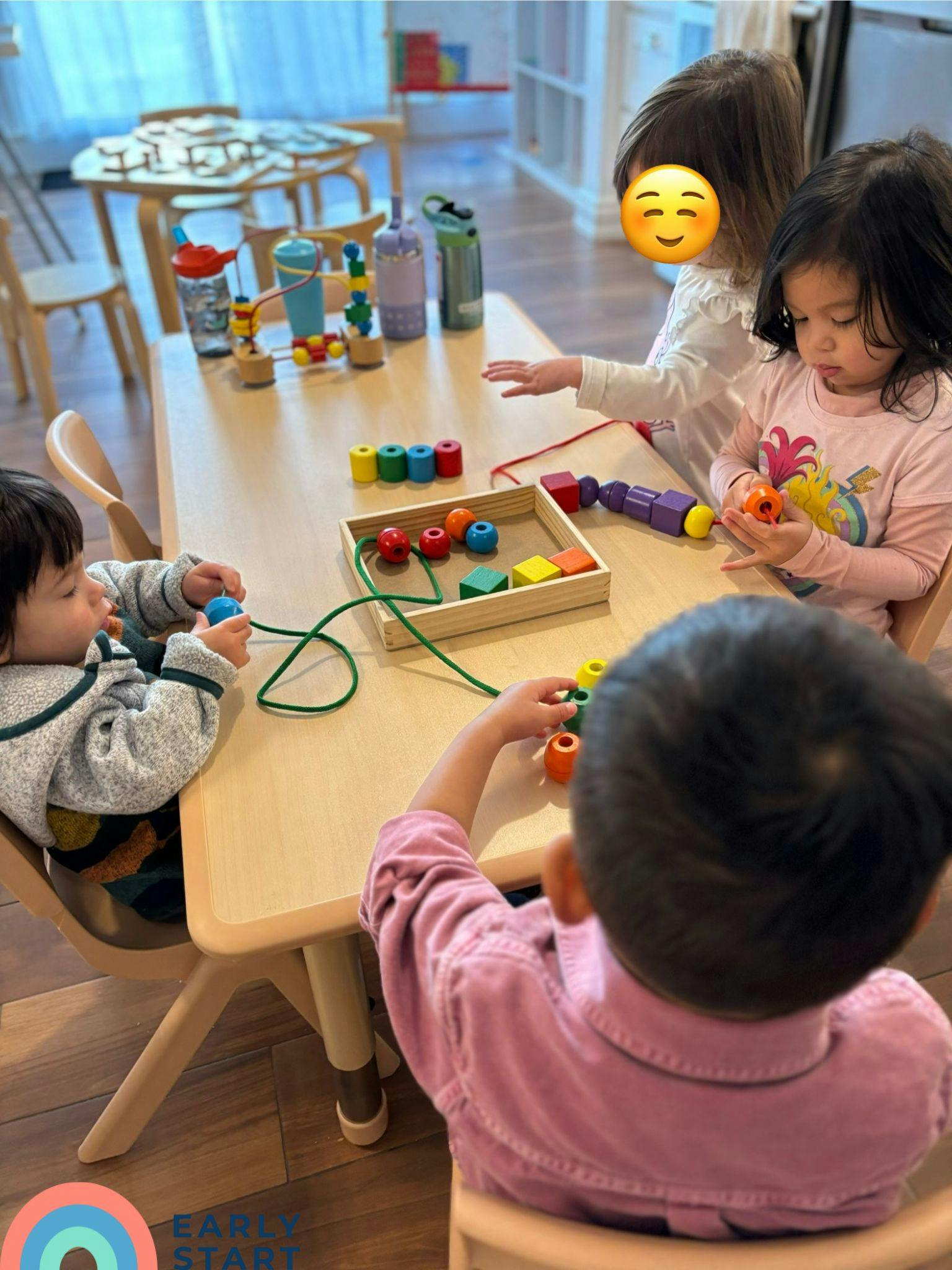 Children playing with colorful lacing beads at a table
