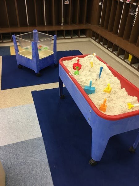 Two sand tables with sand and colorful toys in a classroom