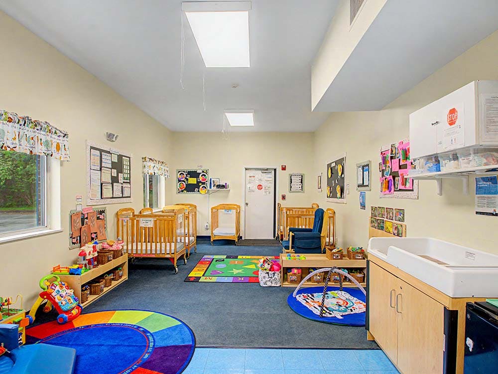 Baby room with multiple cribs, a changing table, and play mats