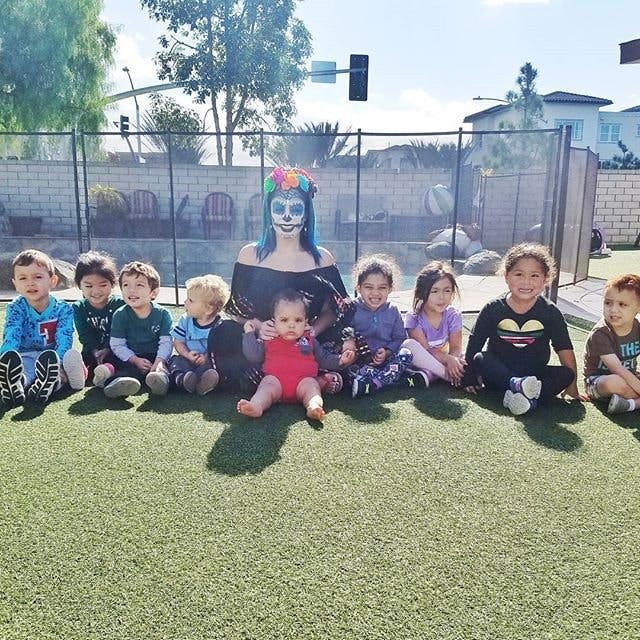 Person in costume with face paint sitting with multiple children