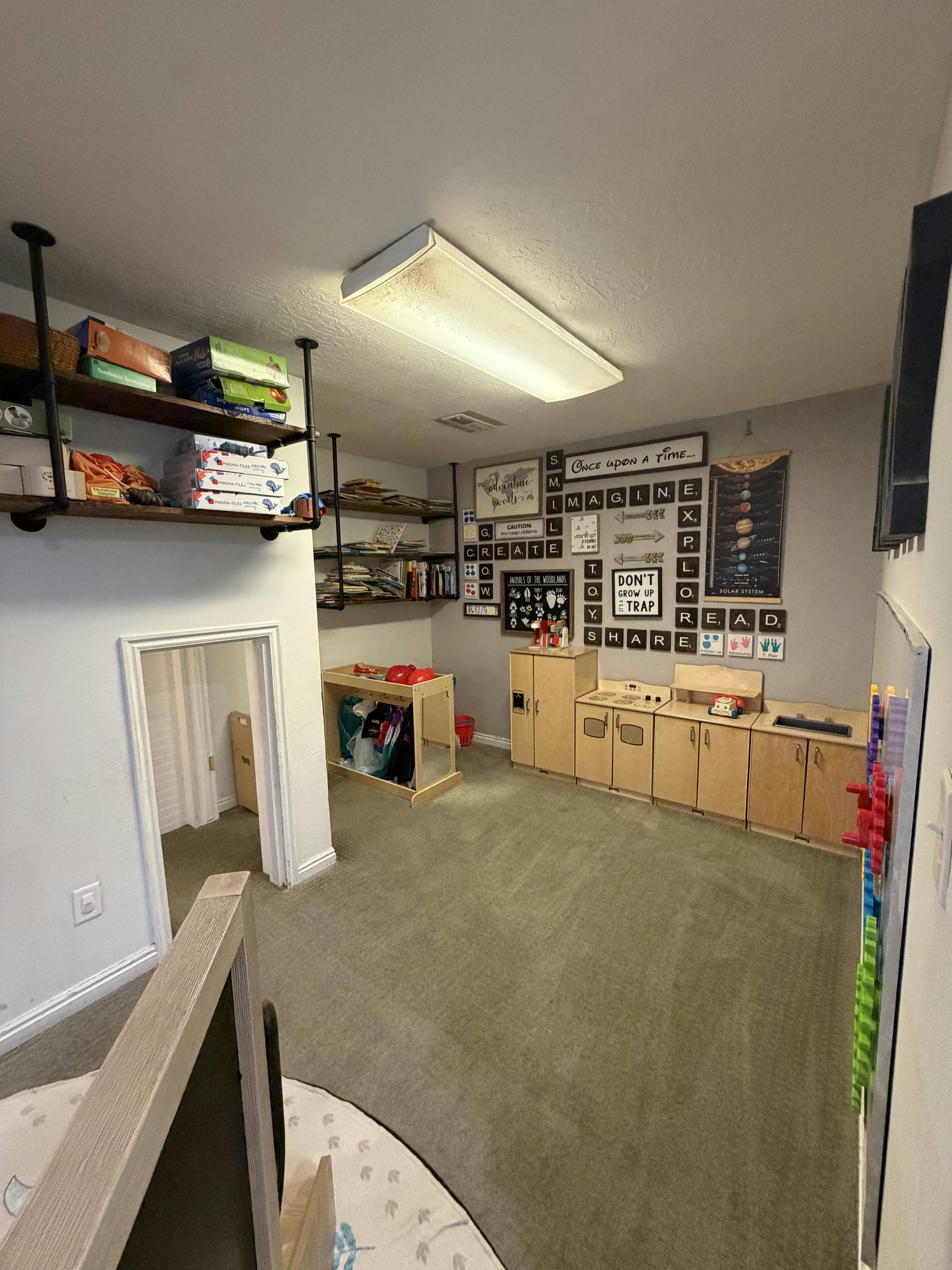 Playroom with shelves, a toy kitchen, and decorative wall signs