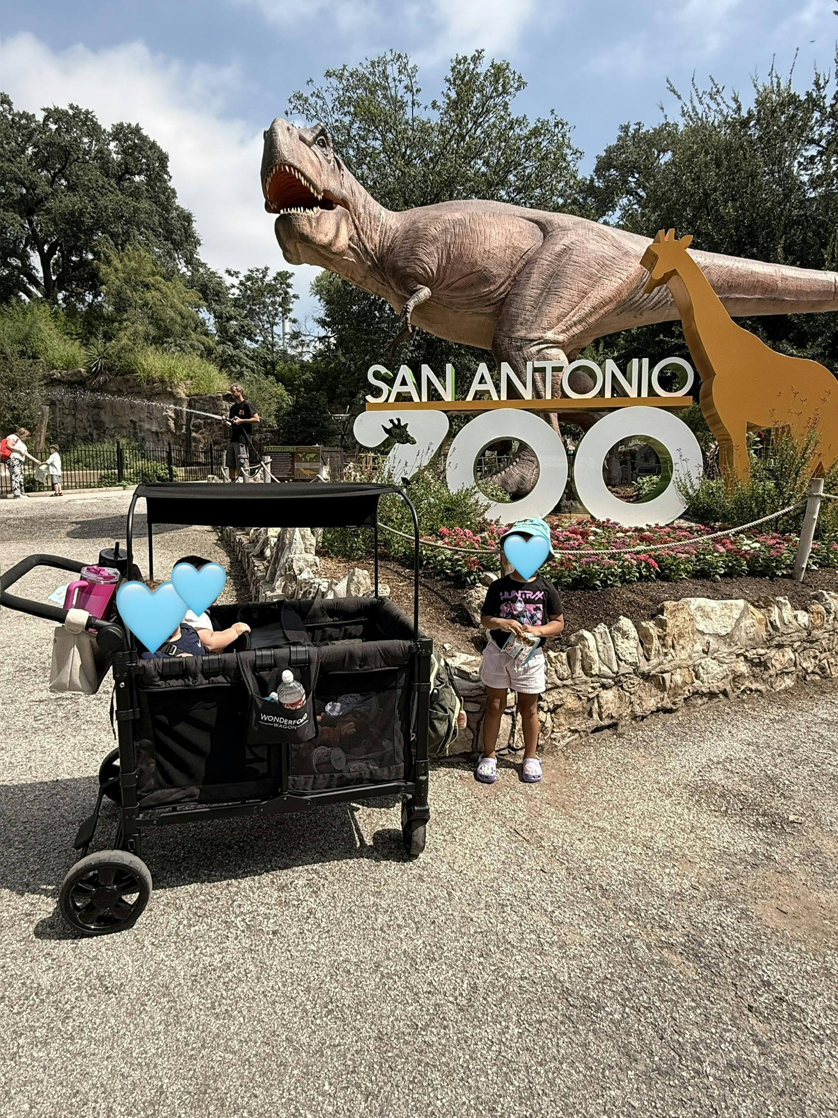 Children near a San Antonio Zoo sign with a large dinosaur statue
