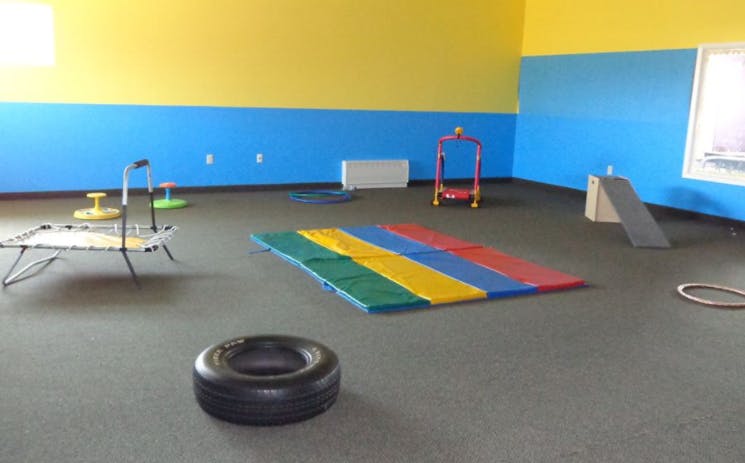 Indoor play area with colorful mats, small trampoline, and ramp