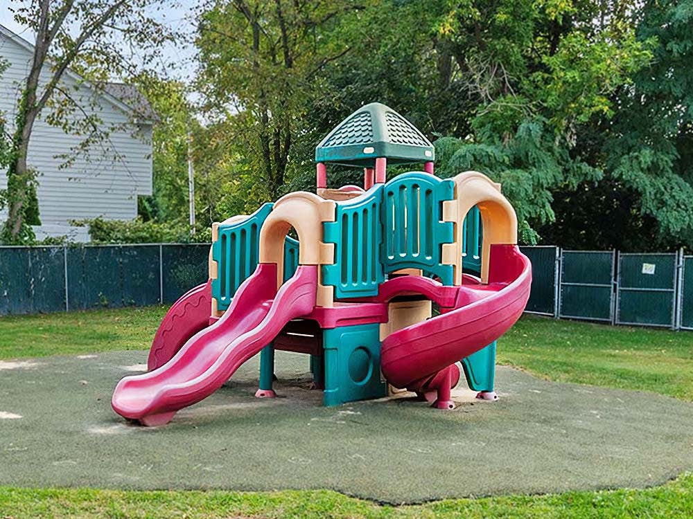 Plastic playground structure with multiple slides on a rubberized surface