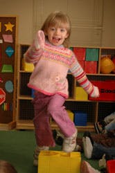 Child standing on a yellow block with arms raised