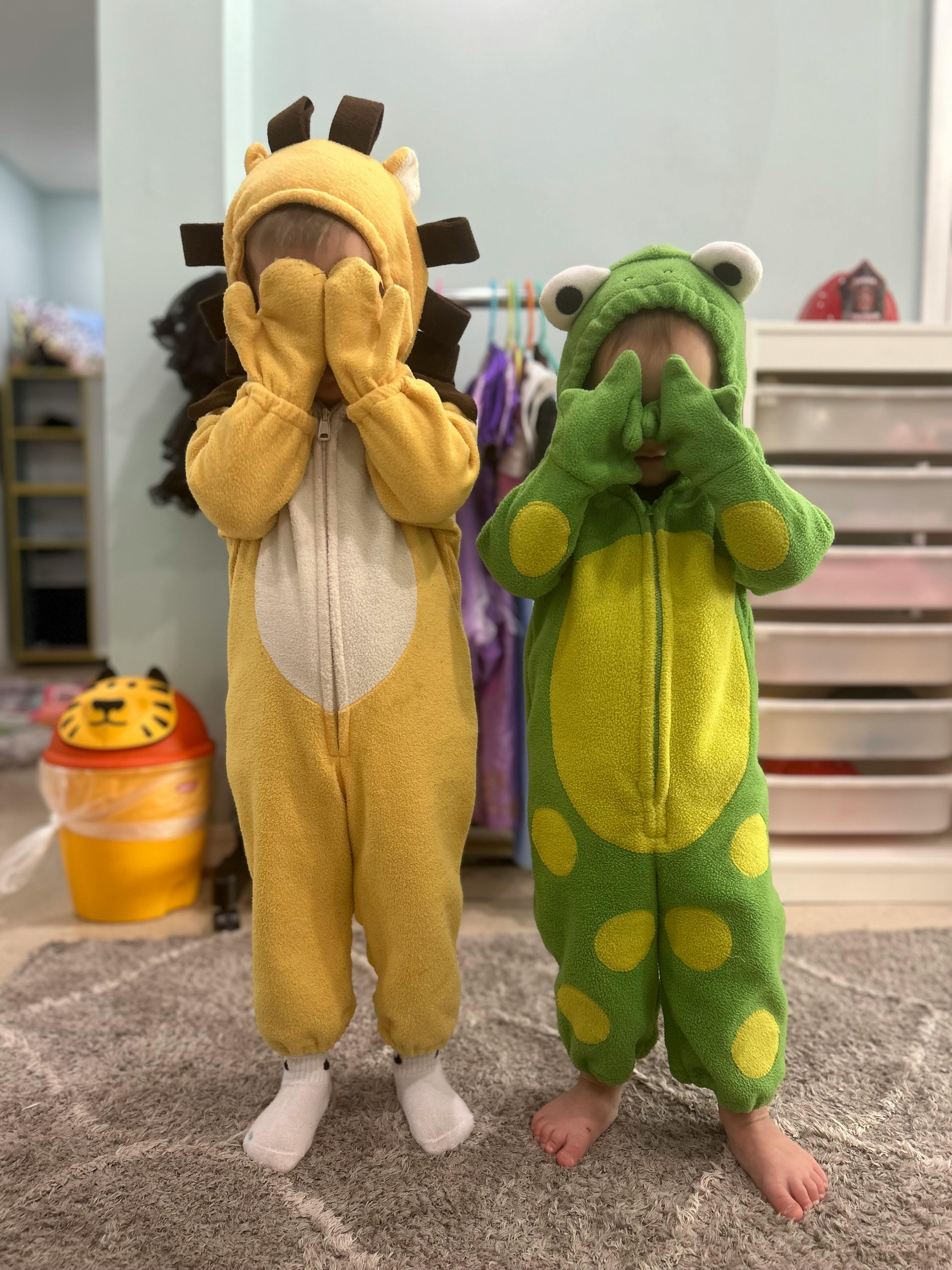 Two children in animal costumes covering their faces with their hands