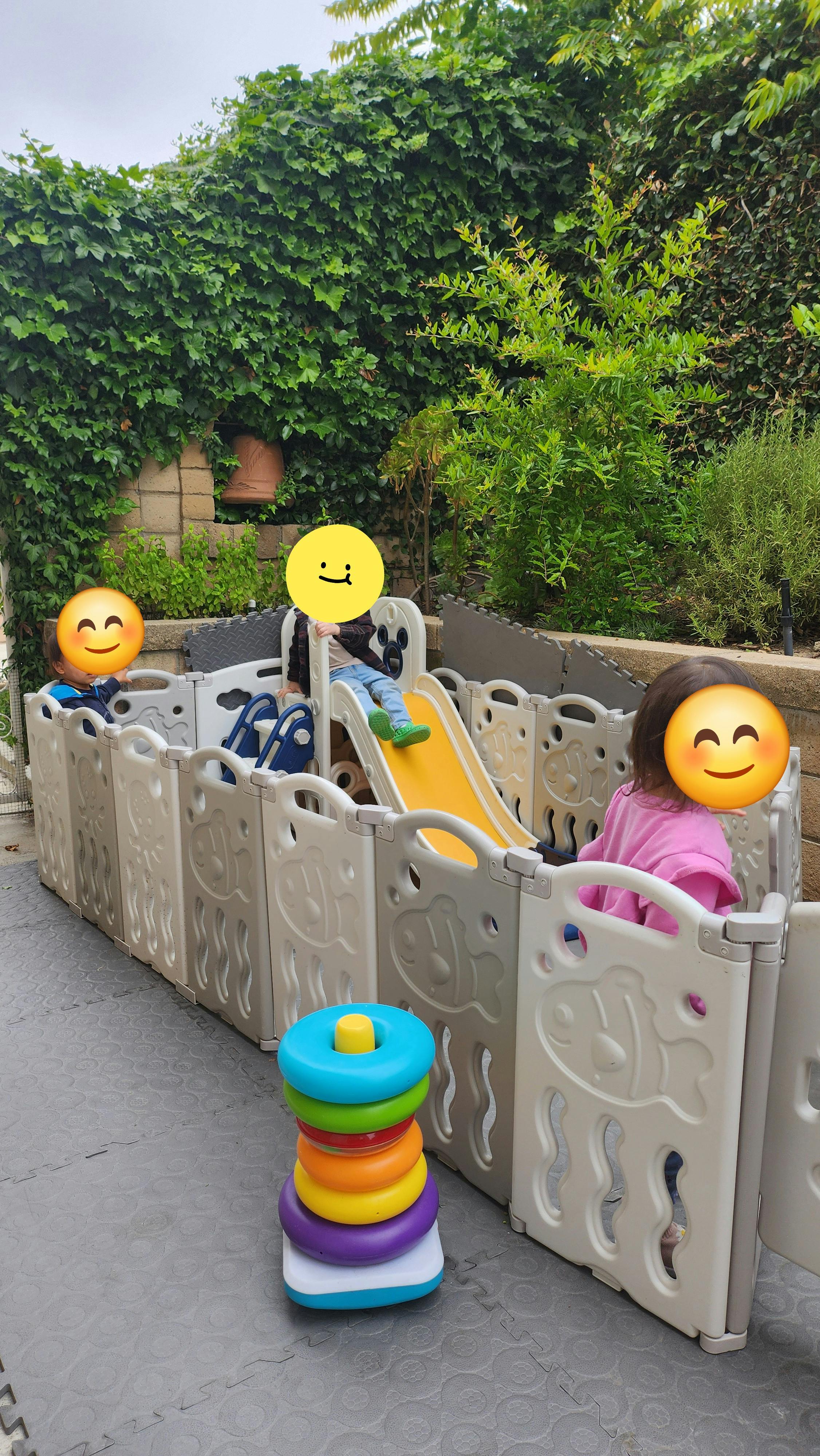 Children playing in an outdoor playpen with a slide