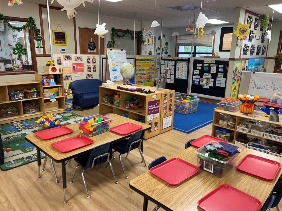 Classroom with small tables and chairs, shelves, and educational displays
