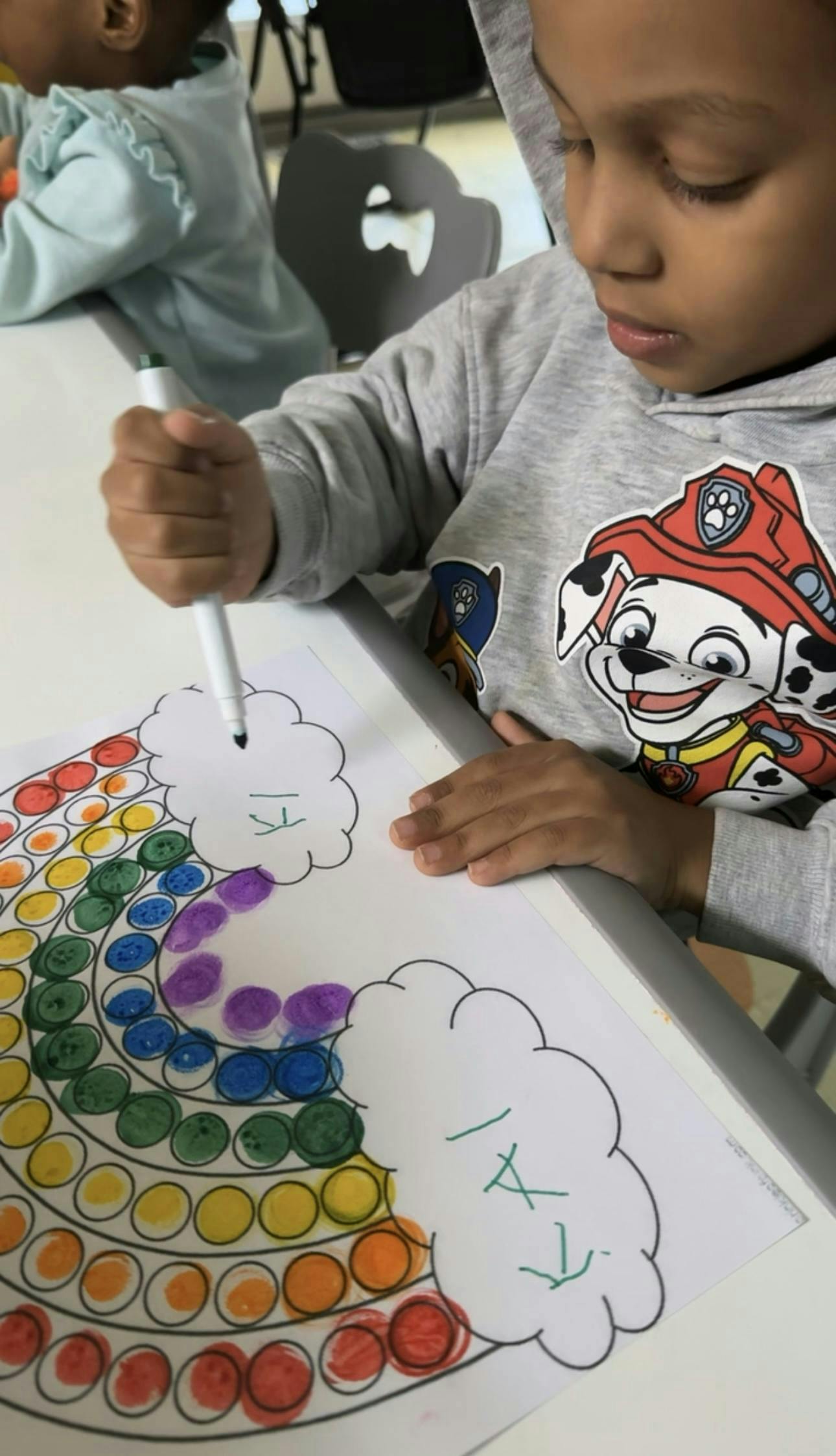 Child coloring a rainbow with a marker