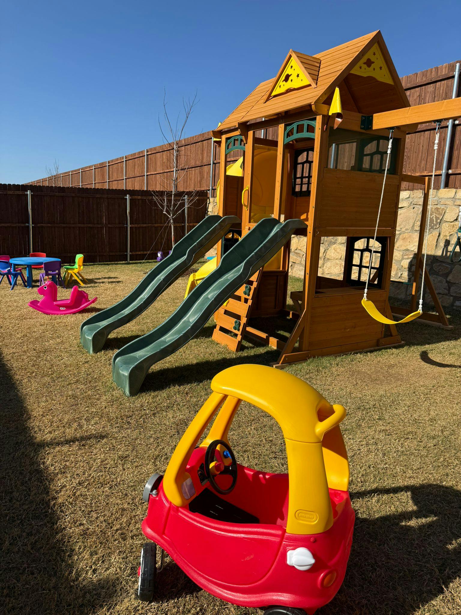 Playground with swings, slides, a ride-on toy car, and a rocking horse