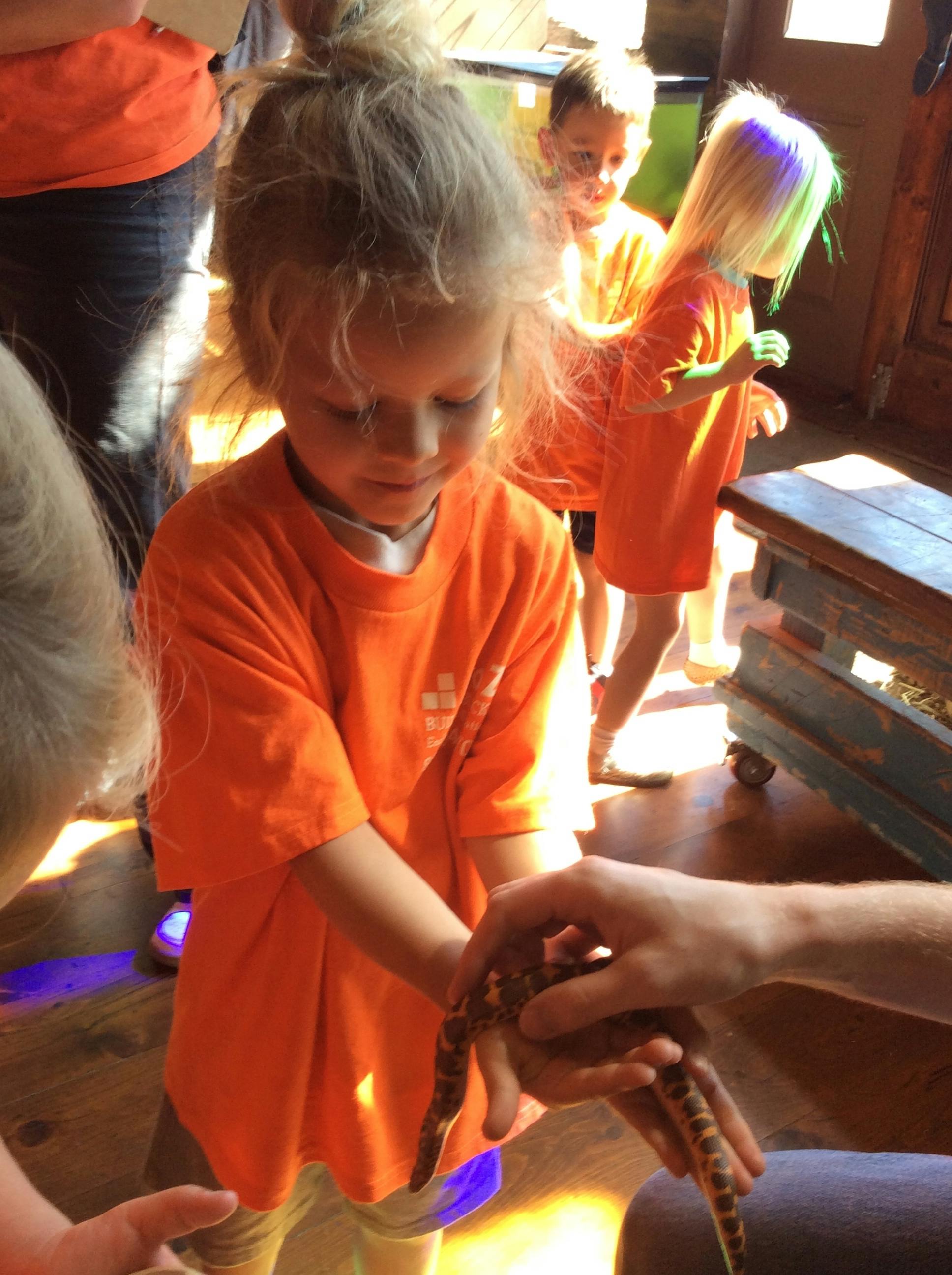 Child holding a small snake while other children watch