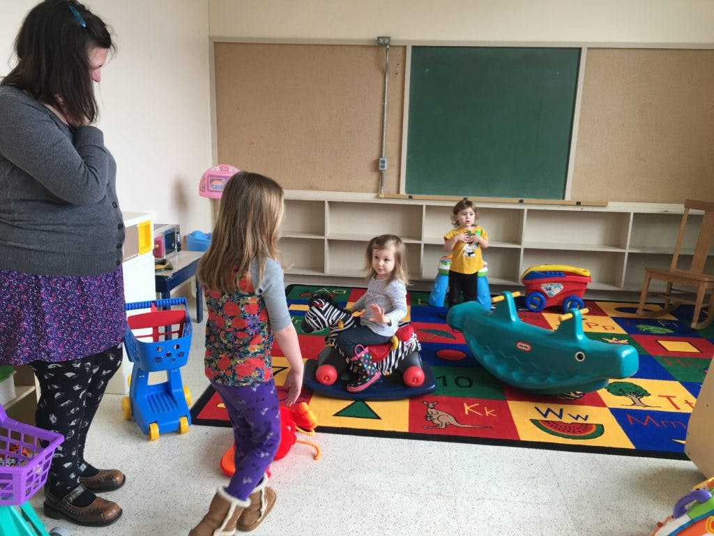 Person and children playing in a room with toys