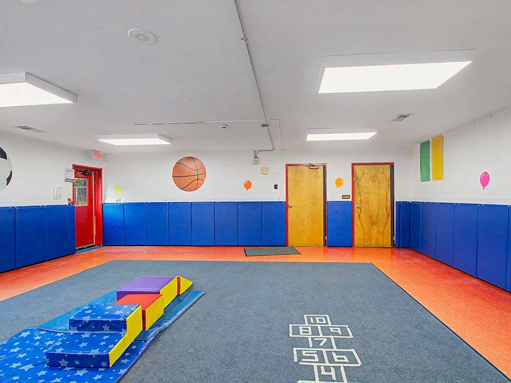 Indoor playroom with gym mats, colorful blocks, and wall decor