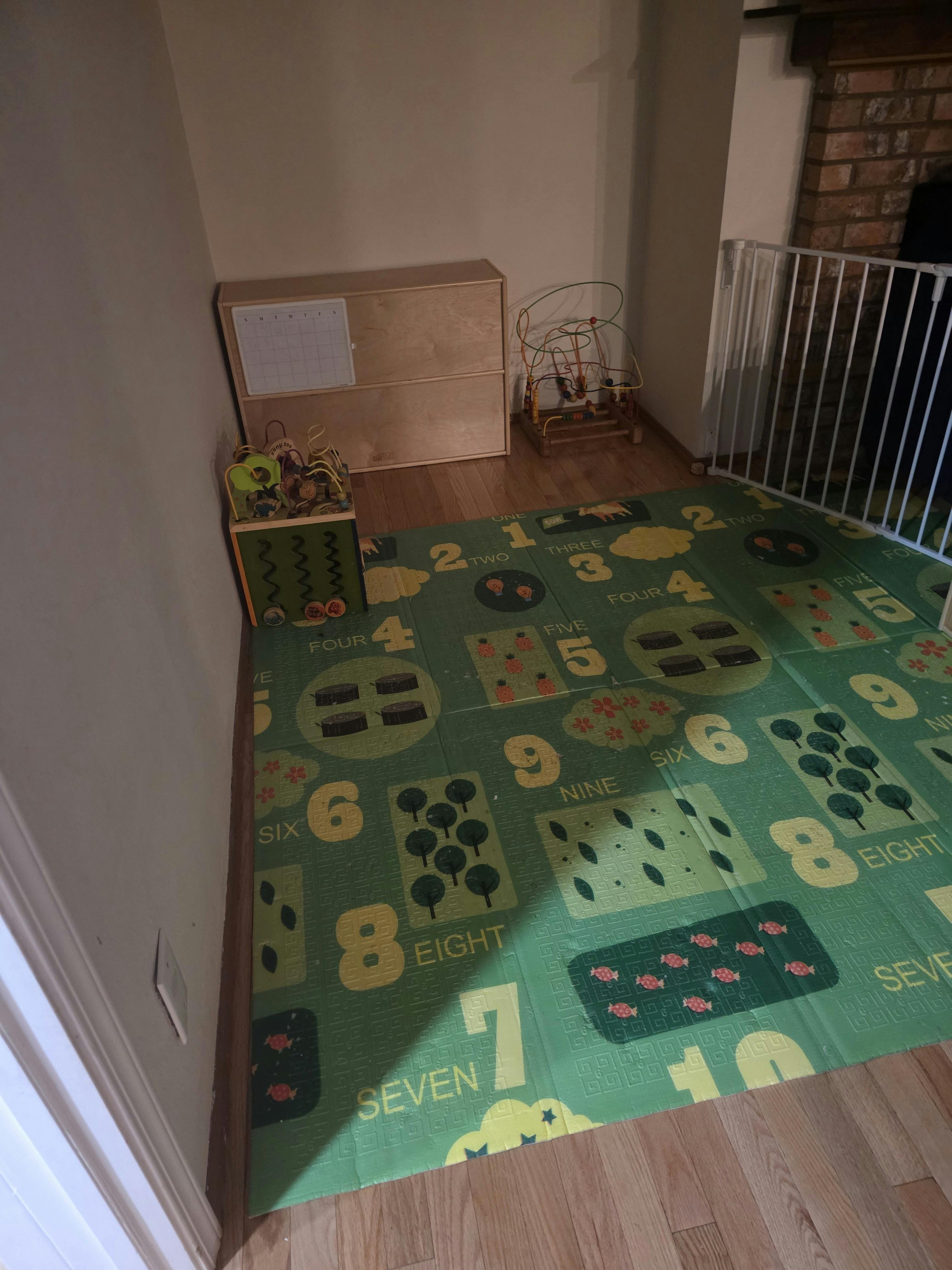 Play area with number-themed floor mat and wooden bead maze toys