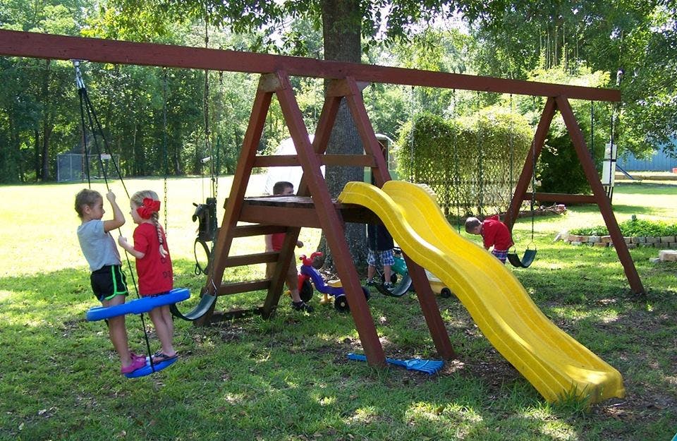 Children playing on a swing set with a slide