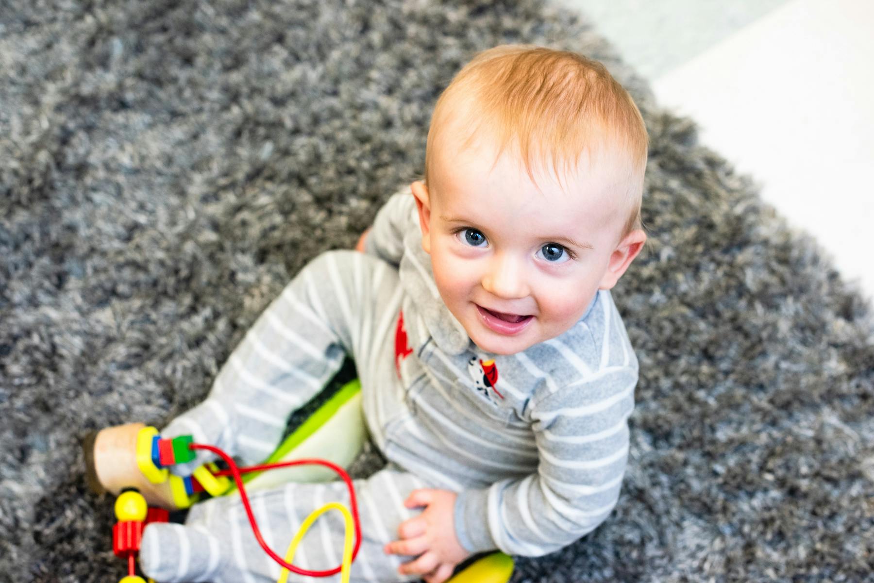 Child sitting on a rug with a toy