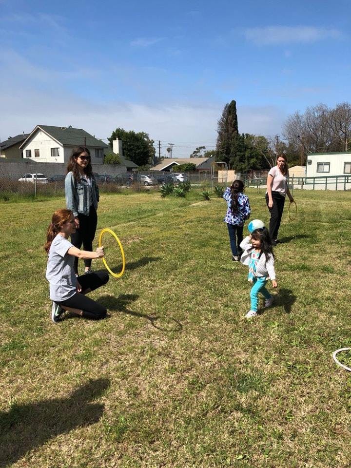 People and children playing with hoops in a grassy field