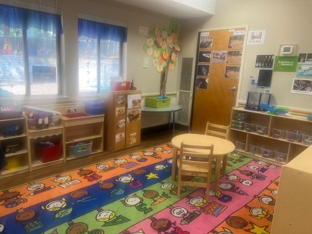 Classroom with a colorful rug, small table and chairs, and play areas