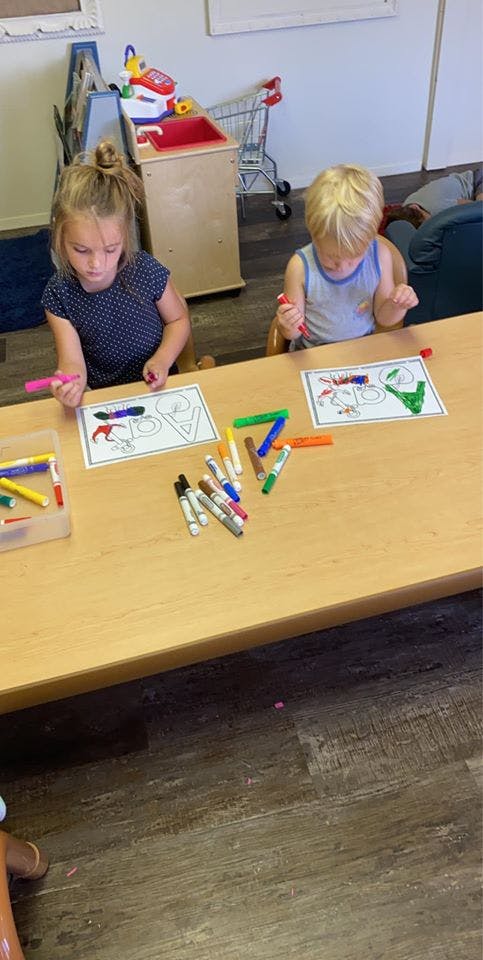 Two children coloring at a table with markers