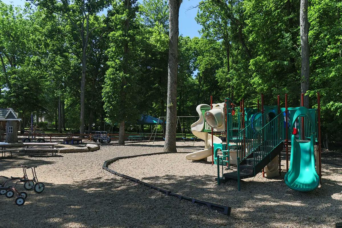 Playground with slides and tricycles in a wooded park area