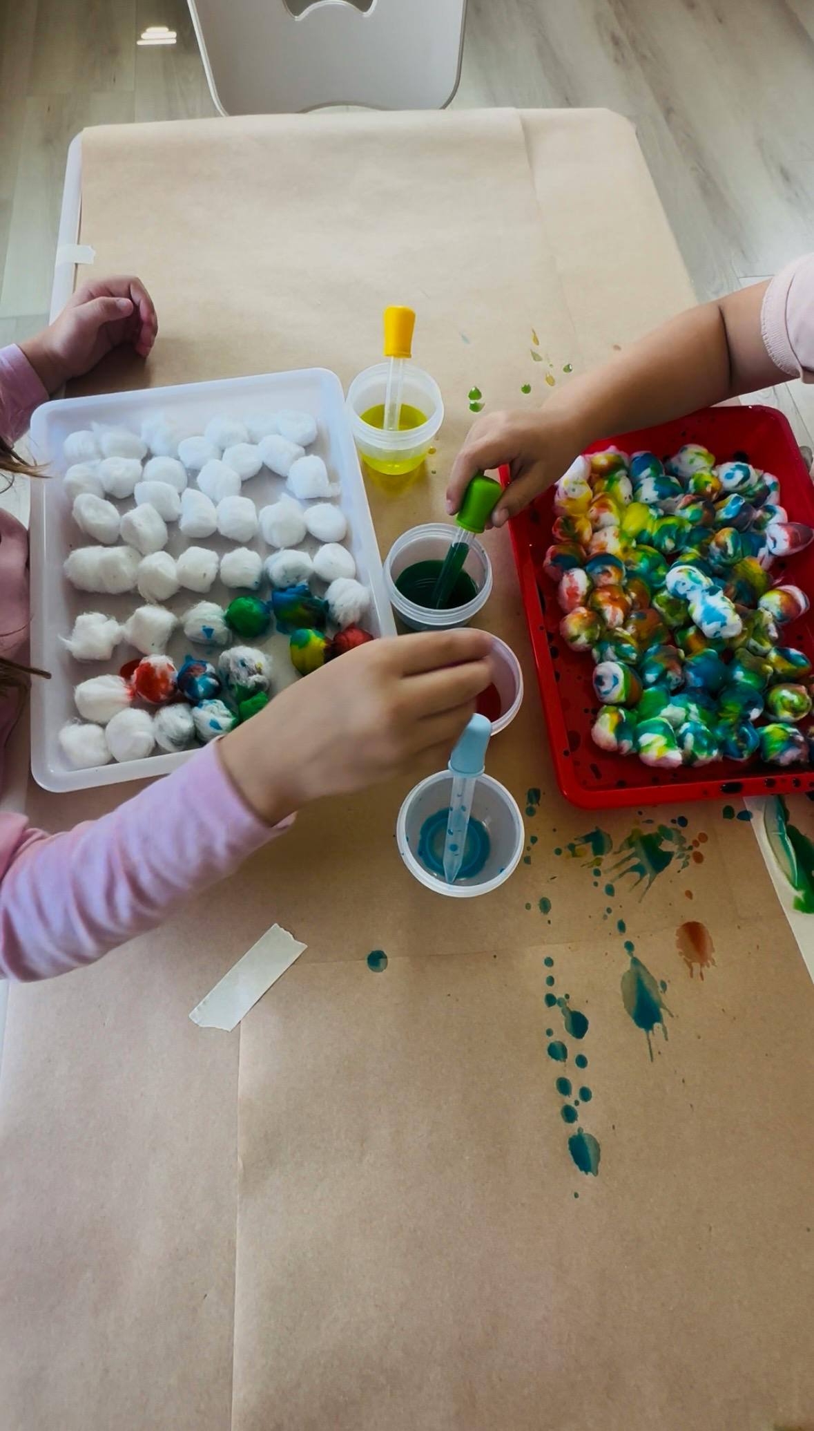 People using droppers to dye cotton balls on trays