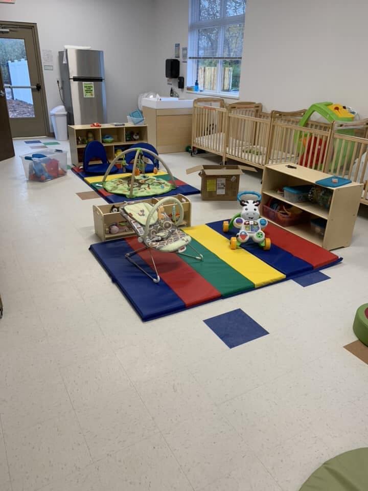 Daycare room with cribs, play mats, and toys