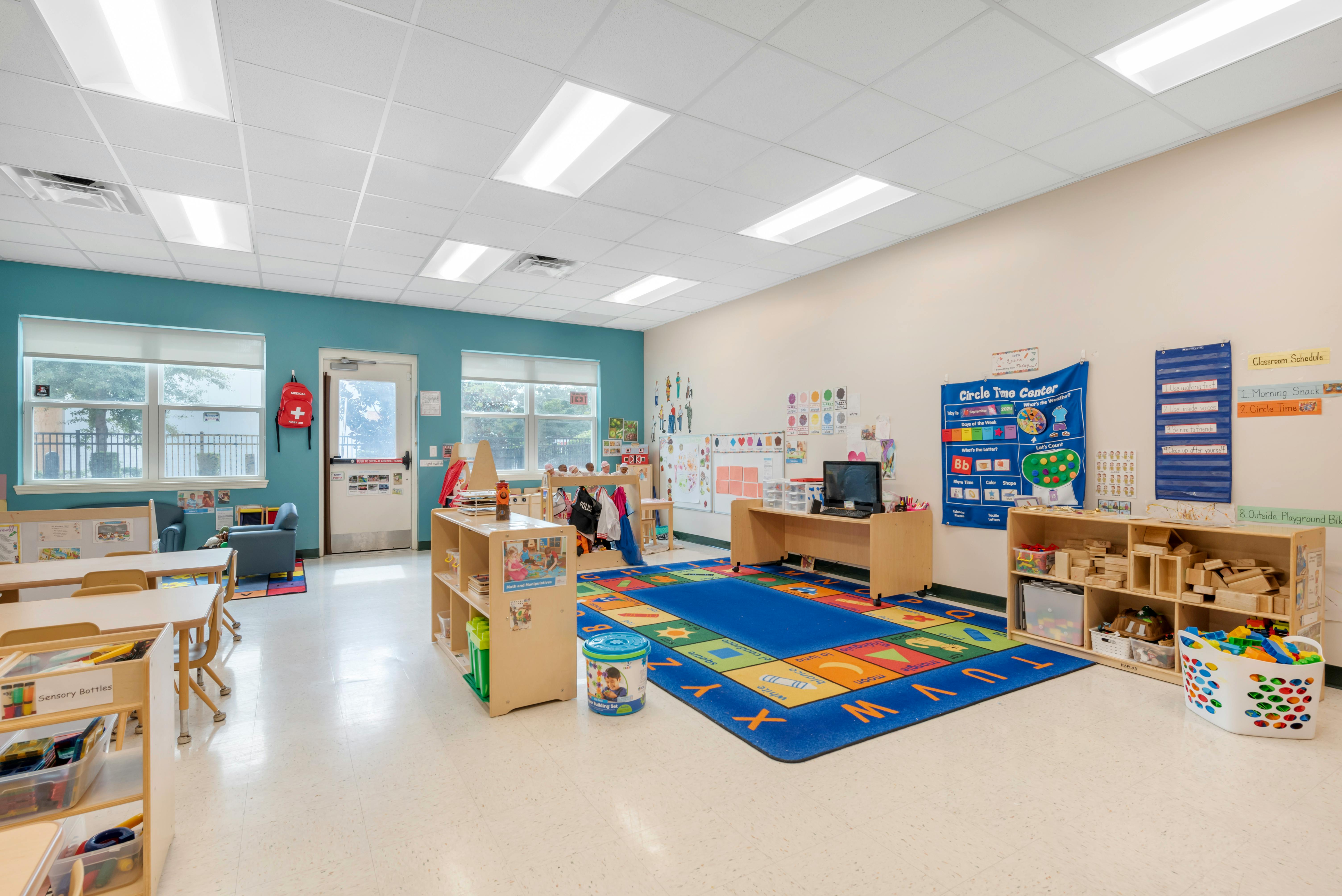 Empty classroom with small tables, chairs, and a colorful rug